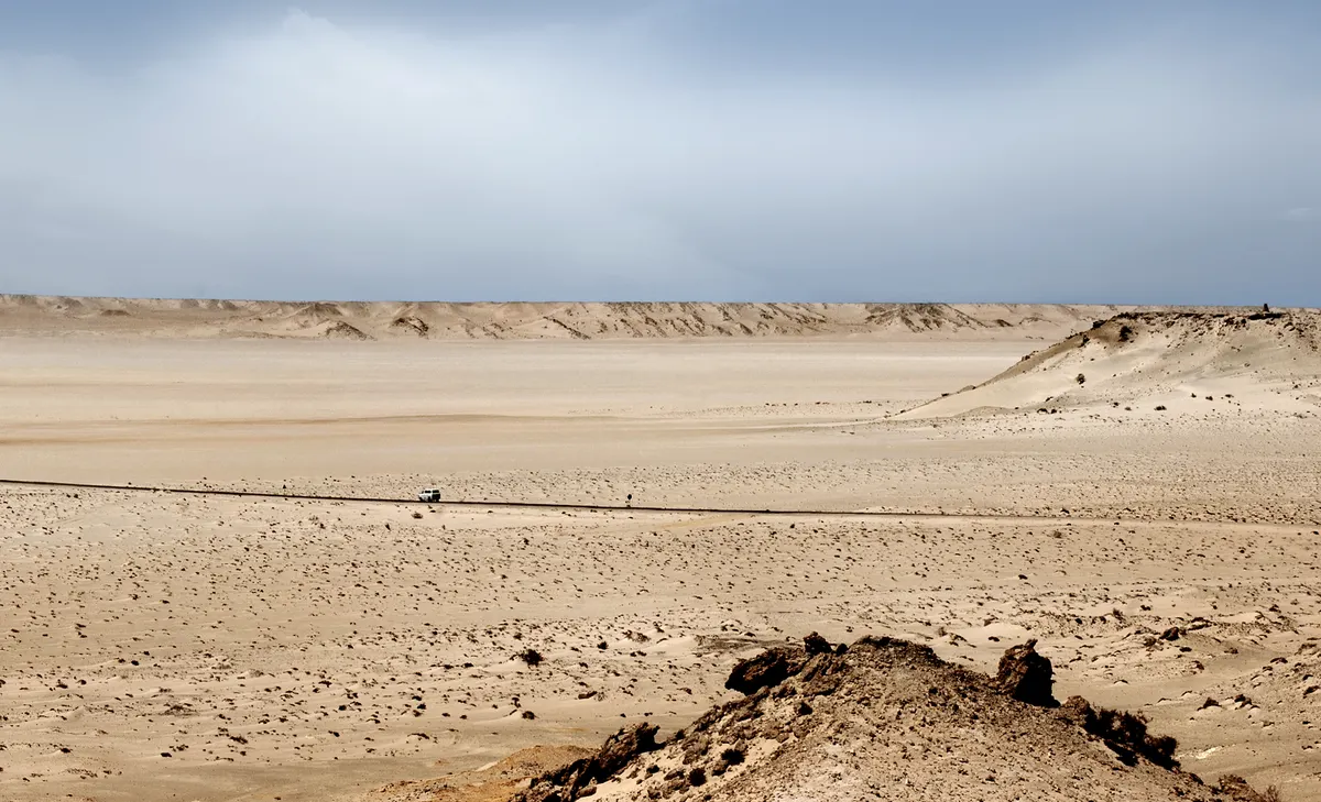 Vast sunlit desert ridges beneath a clear cinematic sky