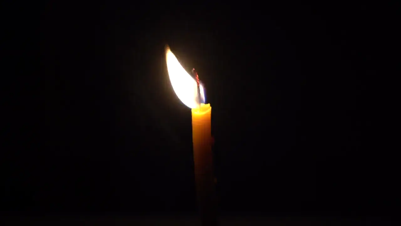 Single candle flame flickering in a warm cinematic close-up